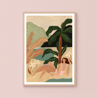 Framed artwork of a woman by a palm tree on a beach with mountains in the background, on a pink wall.