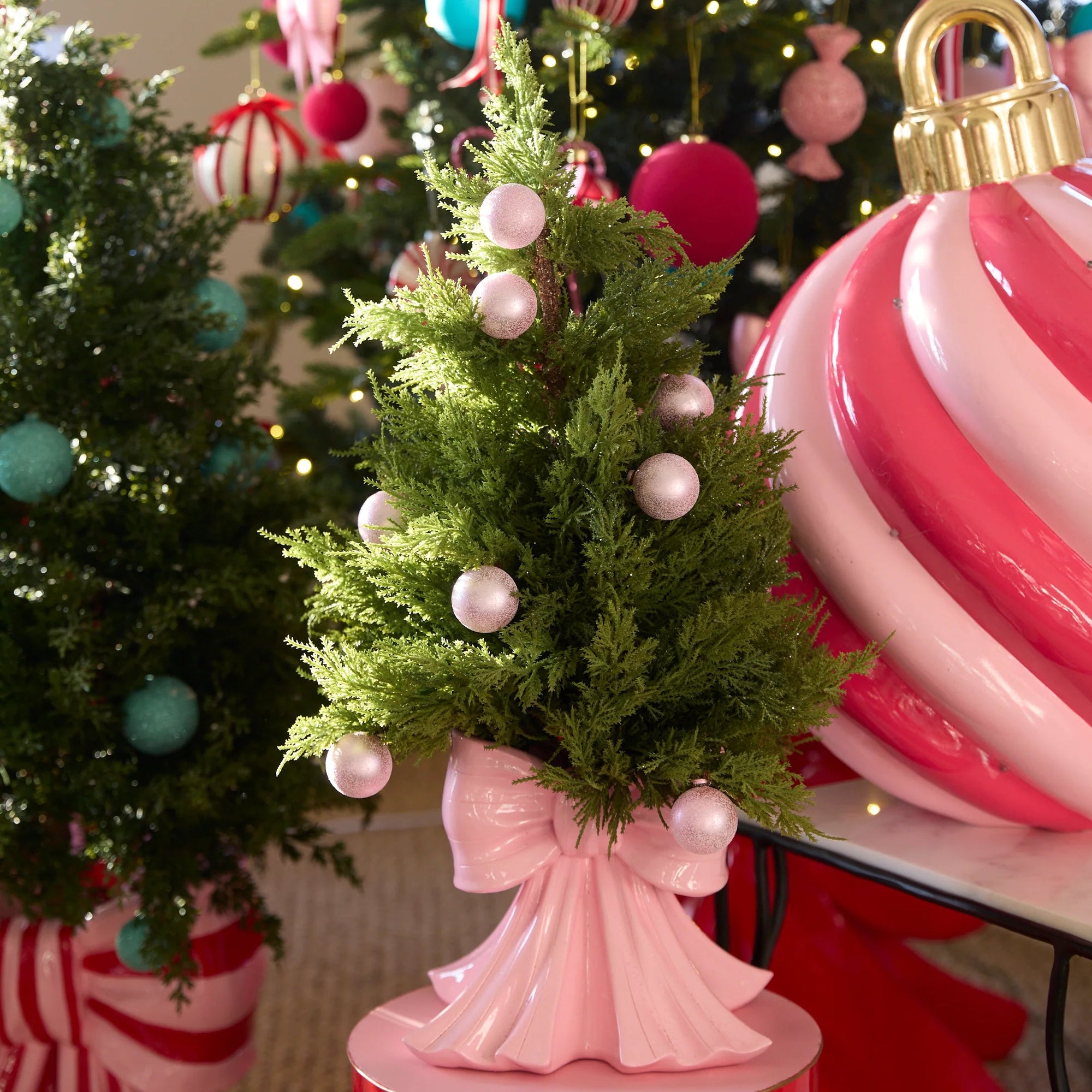 Decorative Christmas scene with a small tree, ornaments, and a large pink ornament.