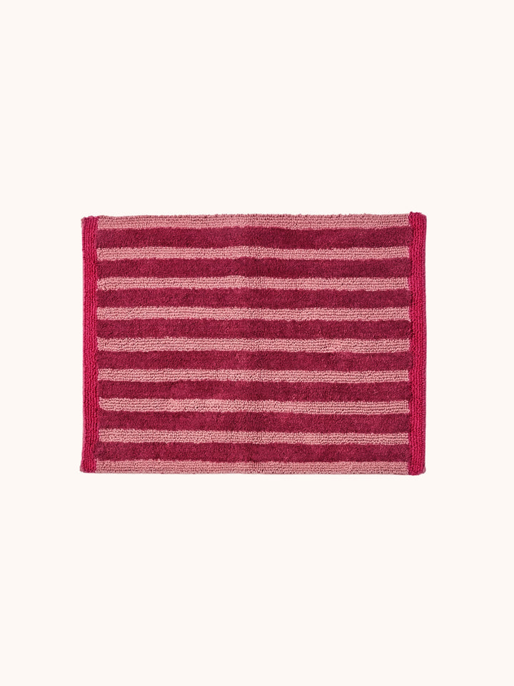 Bonnie and Neil stripe reversible bath mat in burgundy, in a bathroom