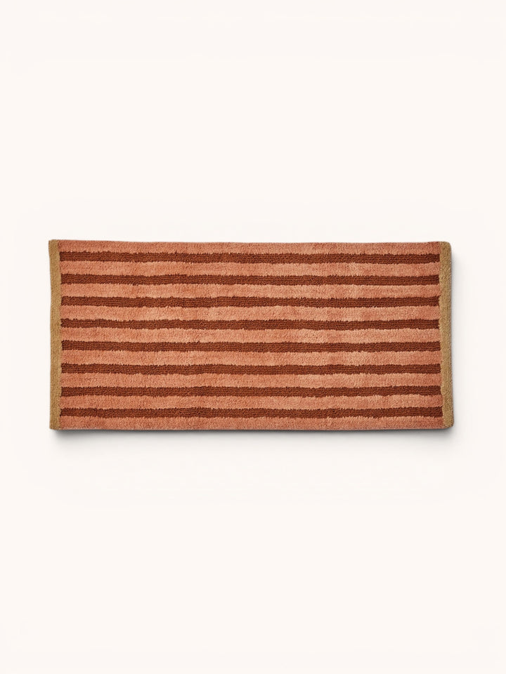 Bonnie and Neil stripe reversible long bath mat in terracotta, in a bathroom