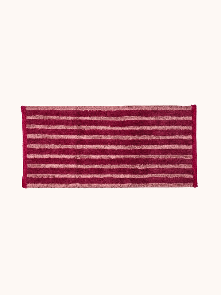 Bonnie and Neil stripe reversible long bath mat in burgundy, in a bathroom